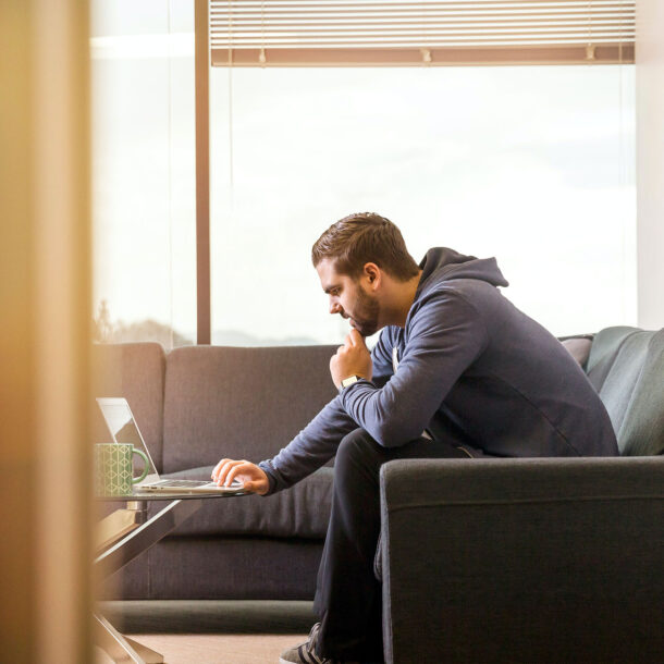 Man sitting on couch looking at his laptop computer.