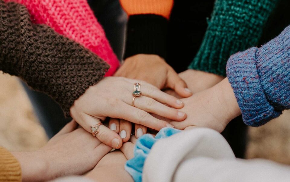 Diverse work colleagues putting their hands together.