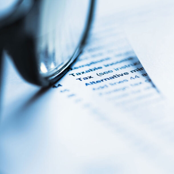 Document with the Word Tax on it with a pair of eyeglasses on top of it.