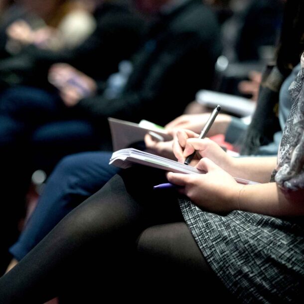 Woman taking notes during a presentation.
