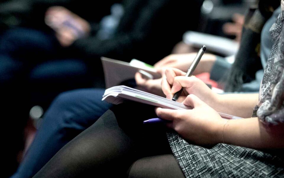 Woman taking notes during a presentation.