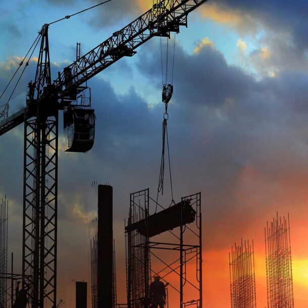 Construction crane carrying work materials at dusk.