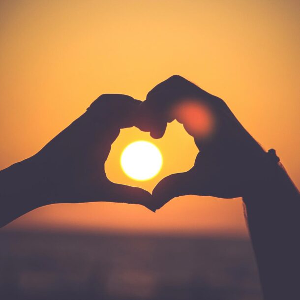 Heart hands with sunset in background.