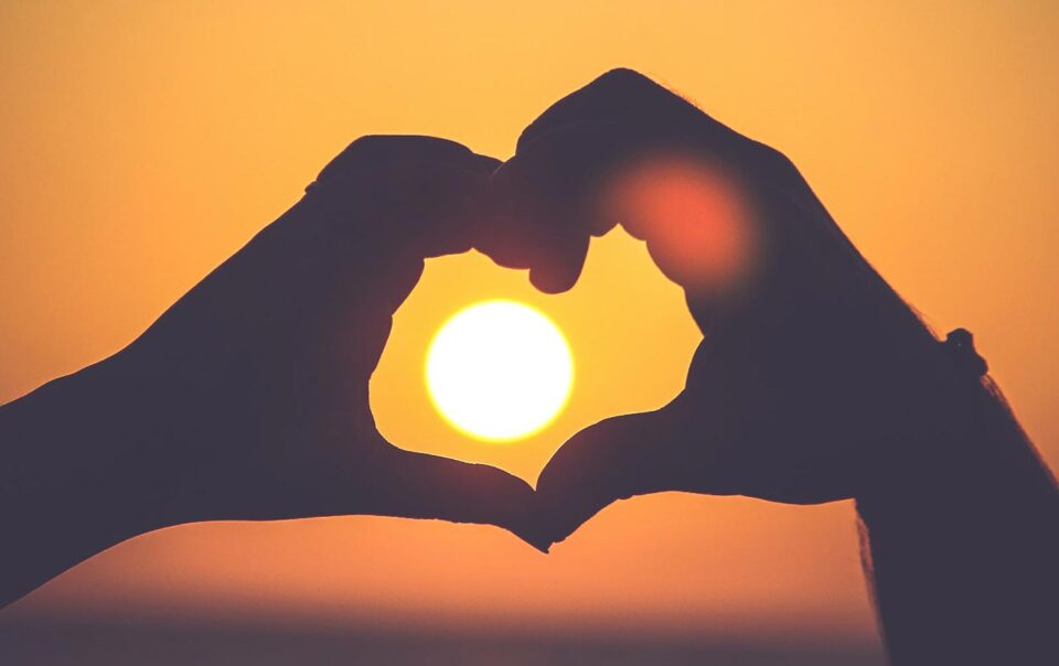 Heart hands with sunset in background.