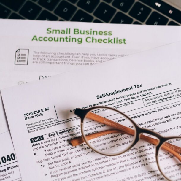 A stack of small business accounting papers sitting on top of a laptop.