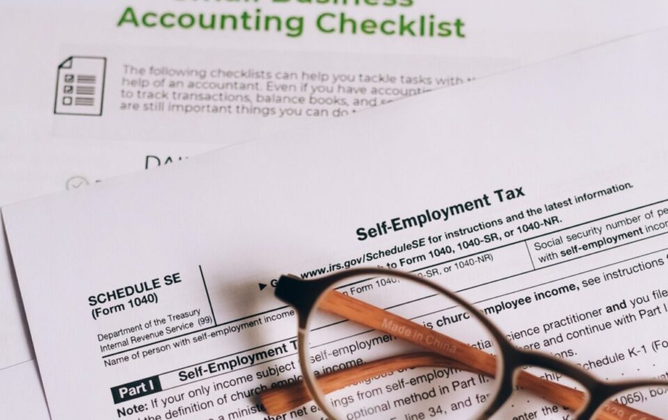 A stack of small business accounting papers sitting on top of a laptop.