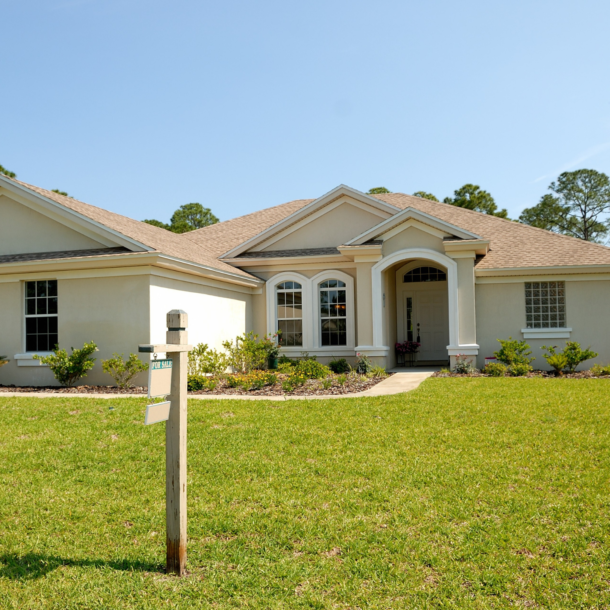 Large white home with a for sale sign in the yard.