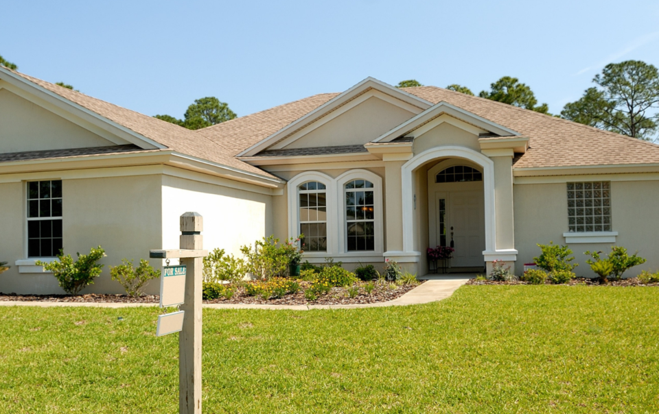 Large white home with a for sale sign in the yard.