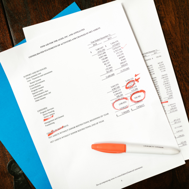 Financial papers and a blue folder sitting on a wooden table.