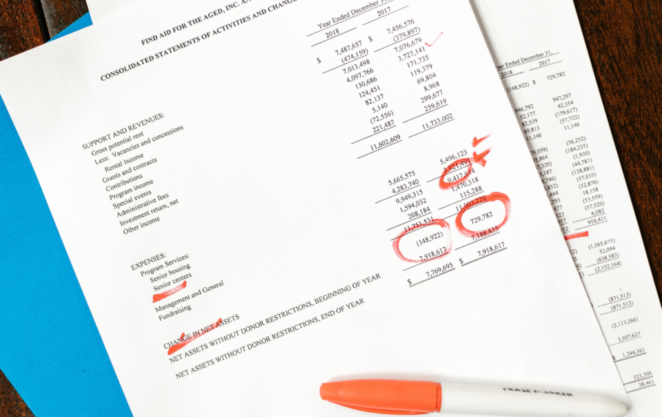 Financial papers and a blue folder sitting on a wooden table.