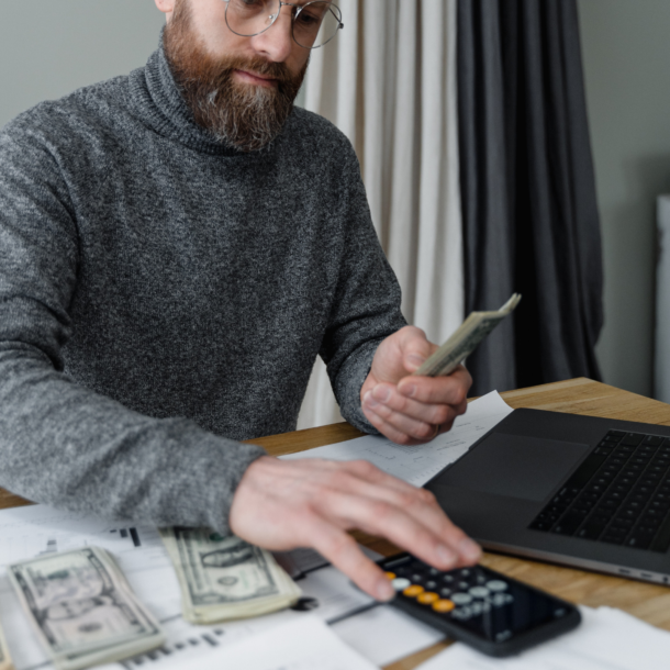Man in Gray Sweater Computing Money