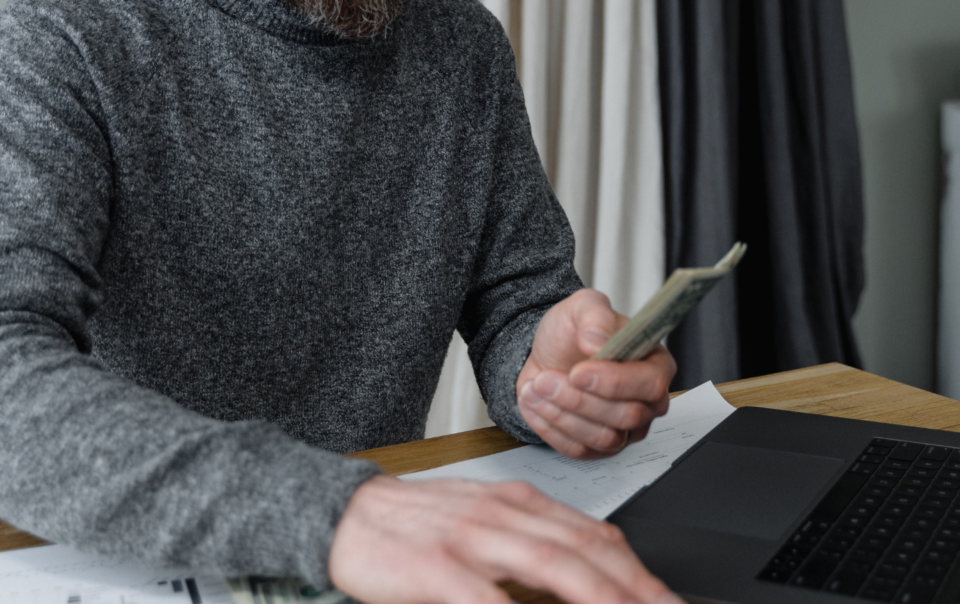 Man in Gray Sweater Computing Money